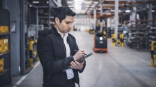 Zaposleni v podjetju Linde Material Handling si v skladišču dela zapiske na tabličnem računalniku.