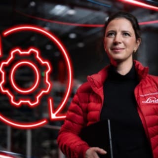 Zaposlena podjetja Linde Material Handling v skladišču, v ozadju rdeča svetleča ikona zobnika.