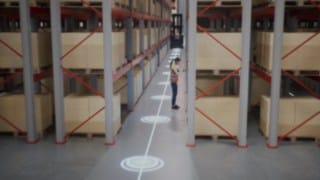 Animacija zaposlene v varnostnem jopiču v skladišču z ozkimi hodniki in varnostnih območij za prepoznavanje oseb