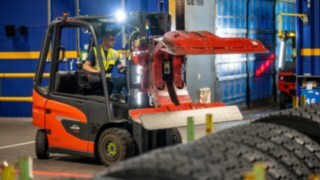 Zaposleni v podjetju Michelin Tyre PLC z objemko za pnevmatike na viličarju Linde E20 zgrabi kup pnevmatik.