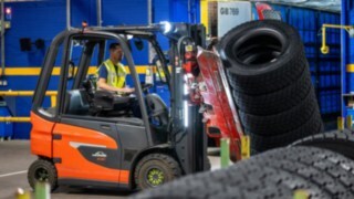 Zaposleni v podjetju Michelin Tyre PLC z objemko za pnevmatike, nameščeno na viličarju, zgrabi kup pnevmatik.