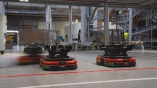 Trije avtonomni mobilni roboti (AMR) podjetja Linde MH vozijo po skladišču
