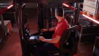 Voznik sedi v ergonomski kabini regalnega viličarja Linde MH Ri16.