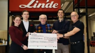 Pet ljudi stoji skupaj in v rokah drži velik ček v vrednosti 10.000 evrov, ki ga je podjetje Linde naslovilo na združenje Aschaffenburger Kinderträume.